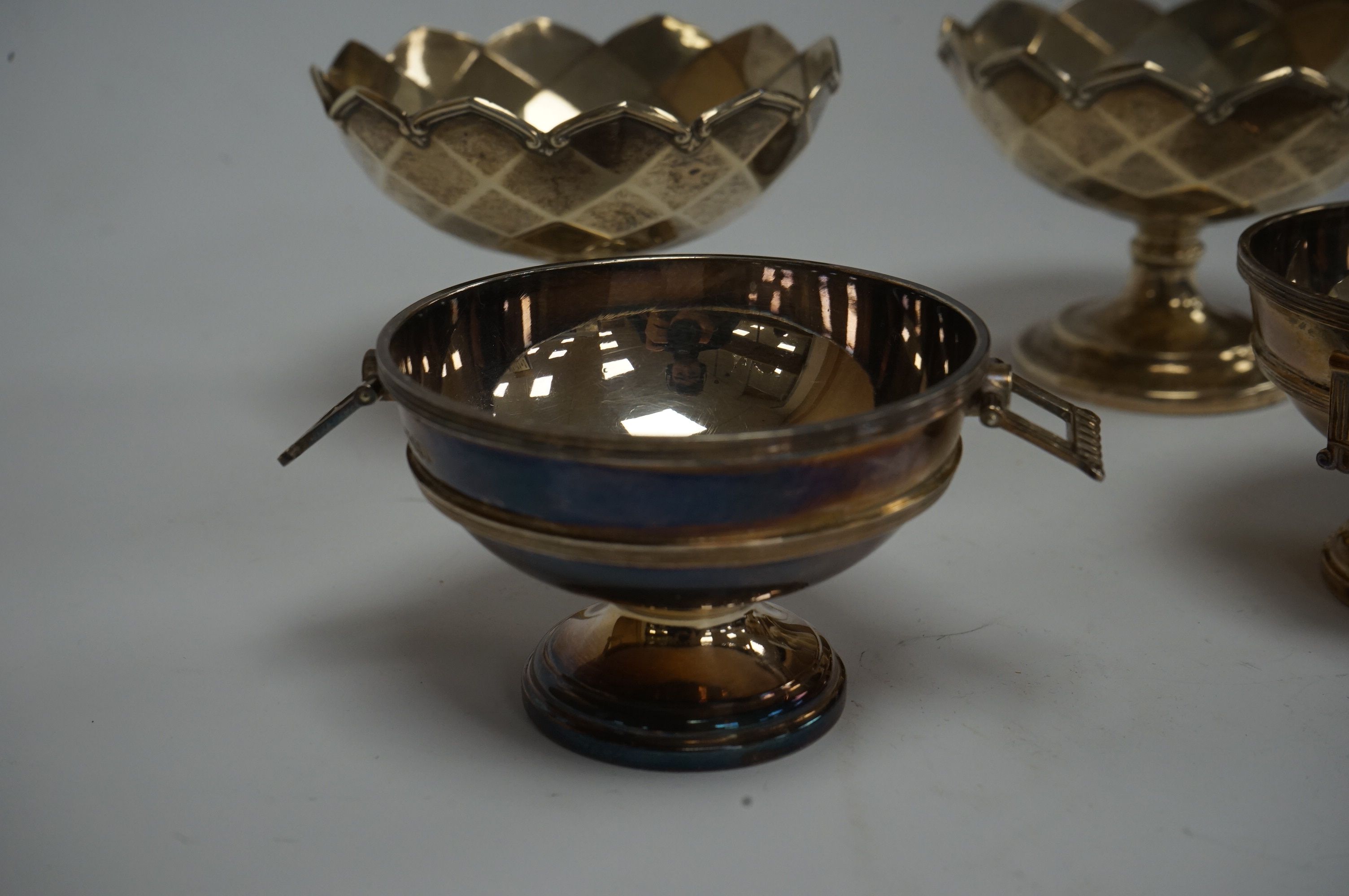 A pair of Elizabeth II silver two handled circular pedestal salts, by Walker & Hall, Sheffield, 1964, diameter 78mm, together with a small pair of George V silver pedestal bowls, Mappin & Webb, Birmingham, 1928, 10.3oz.